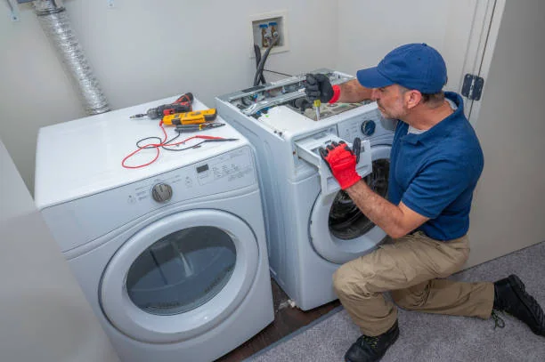Technician diagnosing a residential clothes dryer beside a washer